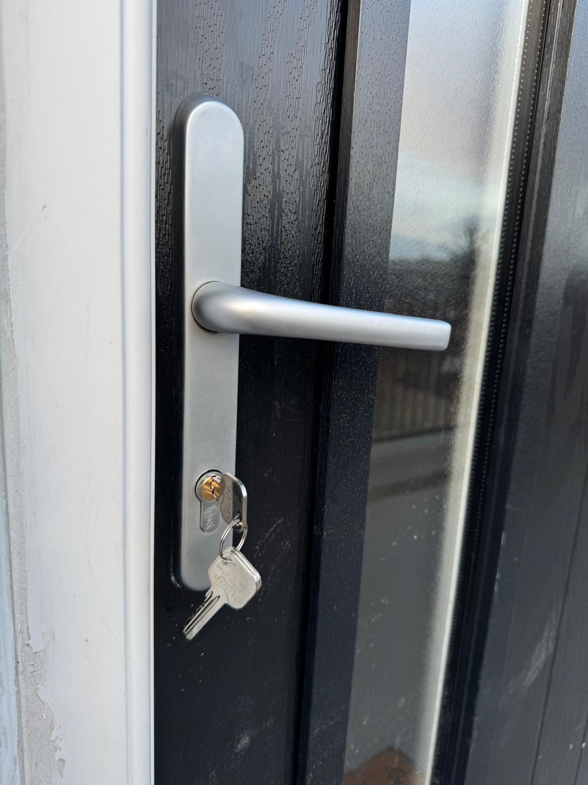 Silver lever handle and security plate installed on a black composite door