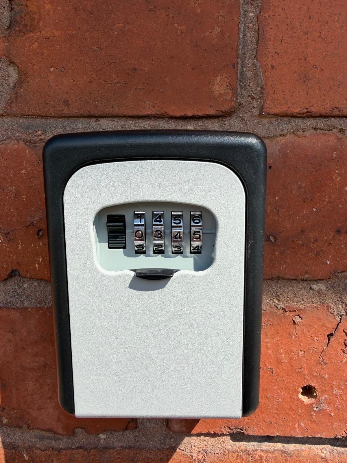 Wall-mounted combination key safe fitted to brick exterior for tradesman access